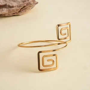Vue détaillée d'un bracelet de bras doré à spirale carrée géométrique sur fond beige