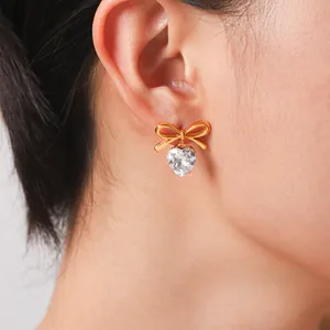 Close-up detail showing 18k gold plated stainless steel bow earrings with heart-shaped zircon