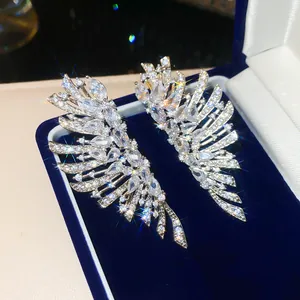 Gros plan de boucles d'oreilles ailes en zircon brillant dans un bel écrin bleu