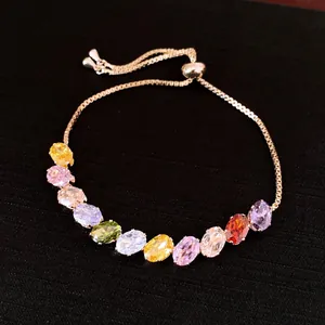 Nahaufnahme eines goldfarbenen verstellbaren Armbands mit bunten ovalen Zirkonia-Steinen