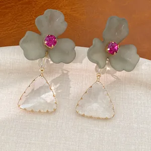 Gedetailleerde macro-opname van acryl bloemoorbellen met fuchsia kristal en driehoekige hangers.