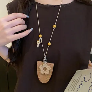 Détail d'un collier bohème avec perles en bois et pendentif fleur sur support liège