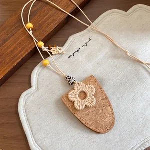 Gros plan d'un collier bohème avec pochette en cuir de liège et breloque fleur tissée