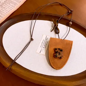 Détail d'un ours léopard sur un collier avec pochette en cuir marron vintage
