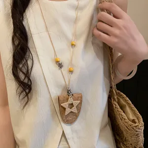 Collier bohème en cordon de cuir avec breloque étoile tissée et détail de clip à lunettes.