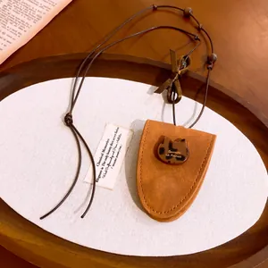 Vue détaillée d'un collier porte-lunettes en cuir marron avec un charme de chat en écaille