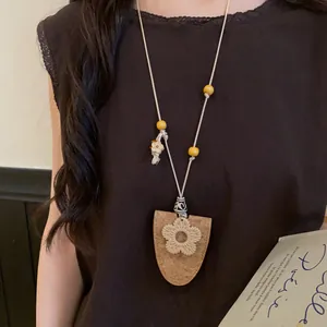 Sautoir style bohème avec cordon en cuir et pendentif fleur porté par un mannequin