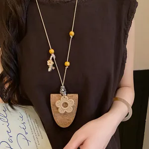 Gros plan d'un collier bohème en cordon de cuir avec fleur tissée et pendentif en liège