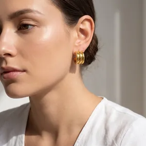 Model wearing elegant gold triple-layered C-shaped hoop earrings in minimalist style
