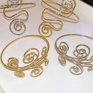 Nahaufnahme von gold- und silberfarbenen, hohlen, spiralförmig gedrehten Metallarmreifen