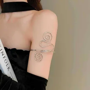 Elegante Detailansicht einer minimalistischen goldenen Spiral-Metall-Armspange am Oberarm