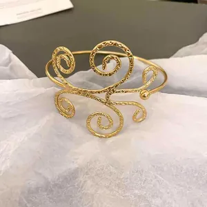 Detailansicht eines goldenen hohlen Metallarmreifs mit gehämmerten Wirbeln