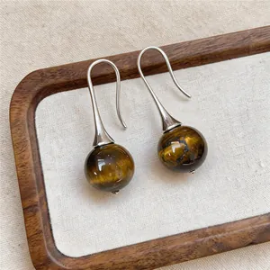 Close-up van retro tijgeroog steen bal oorbellen met zilverkleurige haken