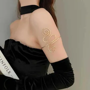 Detailansicht eines goldenen Metall-Armreifs, getragen am Oberarm mit schwarzem Handschuh.