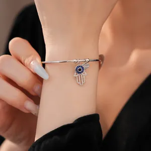 Detailansicht eines silbernen Hamsa-Hand-Armreifs mit Zirkonia und Liebesherz-Anhänger