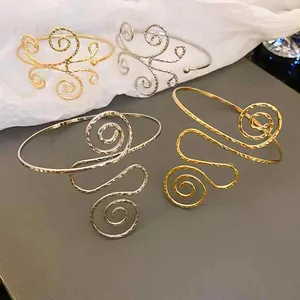 Detailansicht goldener und silberner ausgehöhlter Metallarmreifen mit Spiralmuster.