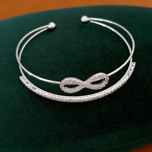 Detailansicht eines silberfarbenen Infinity-Armreifs mit funkelnden Zirkonia-Steinen