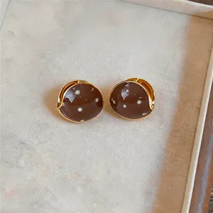 Elegante braune Emaille-Ohrringe mit weißen Punkten und Goldrand für Damen im Retrostil