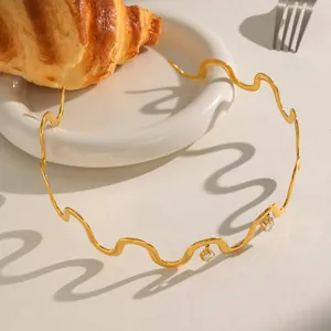 Eleganter goldener Edelstahl Wellenhalsreif mit Kristallanhängern auf dem Tisch.