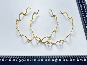 Detaillierte Nahaufnahme goldener gewellter Edelstahl-Halsreif mit zarten Perlen-Akzenten