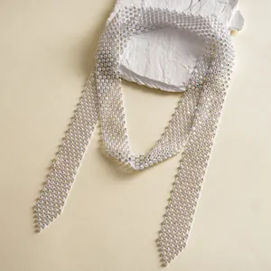 Close-up of a luxury white rhinestone woven tie necklace on a textured stone prop