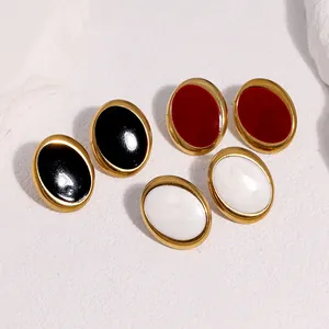Makroaufnahme von ovalen Retro-Emaille-Ohrsteckern in den Farben Schwarz, Rot und Perlweiß