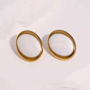Nahaufnahme von ovalen Edelstahl-Ohrsteckern mit weißer Emaille-Einlage im Retro-Look