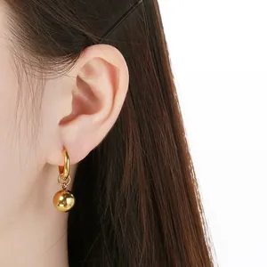 Detailopname van een minimalistische gouden roestvrijstalen baloorbel aan het oor