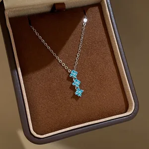 Élégant collier avec trois pendentifs fleurs en zircon bleu dans un écrin marron