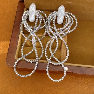 Detailansicht von mehrlagigen Quastenohrringen mit Barockperlen und glitzernden Silberperlen.