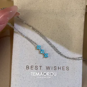 Détail d'un collier en argent avec trois délicats pendentifs fleurs en zircon bleu.