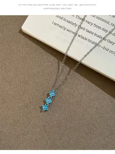 Détail de collier en argent avec trois pendentifs fleurs en zircon bleu sur fond de style