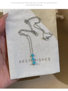 Détail d'un collier en argent avec pendentif fleur en zircon bleu sur pochette cadeau.