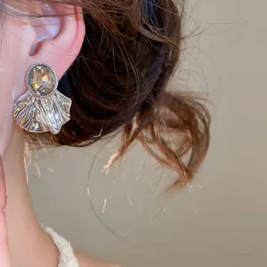 Gros plan de boucles d'oreilles élégantes plissées en forme d'éventail avec pierre