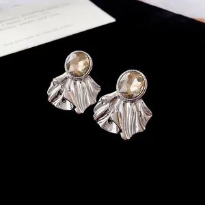 Gros plan détaillé de boucles d'oreilles argentées plissées en éventail avec cristal