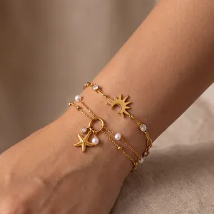 Close-up detail of gold stainless steel bracelets with starfish charm and small pearls
