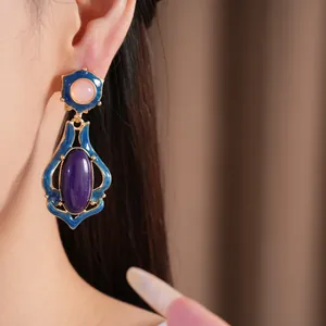 Detailansicht von goldenen Vintage-Ohrringen mit blauer Emaille und lila Harztropfen