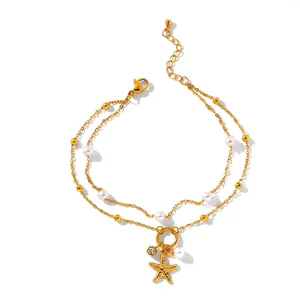 Close-up detail of a gold stainless steel double-layer bracelet with pearls and starfish