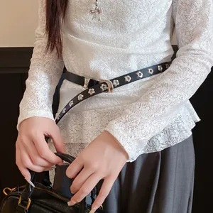 Detail shot of a black vintage leather belt featuring elegant silver flower grommet accents