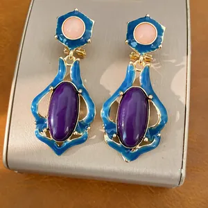 Detailaufnahme von Vintage-Ohrringen mit lila Harzsteinen und blauen Emaille-Rahmen