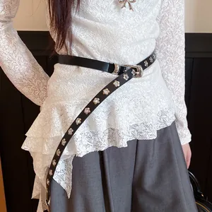 Detail of a French retro black leather belt with elegant silver flower studs on a model.