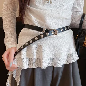 Detail of a black leather belt with silver flower studs on a white lace top