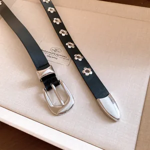 Detailed macro shot of a black leather belt with silver flower-shaped metal eyelets