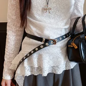 Detail shot of black leather belt with silver flower eyelets on lace top