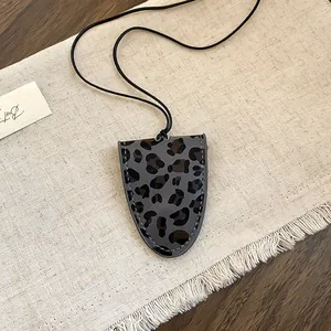 Detail van een retro lederen brillenhouder ketting met een luipaardprint motief.