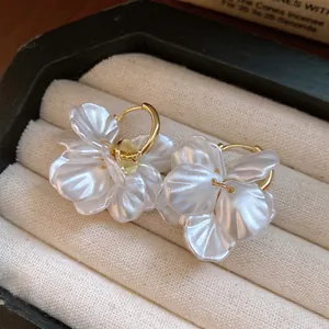 Gros plan sur des boucles d'oreilles pétales de fleurs nacrées avec fermoirs dorés