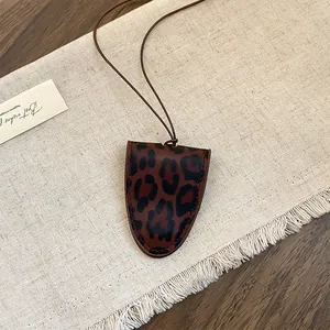 Detail van een vintage brilhaarthouder ketting met luipaardprint op een franje ondergrond.
