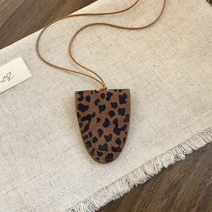Close-up van vintage luipaardprint hanger ketting op een getextureerde linnen achtergrond