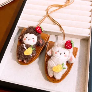 Close-up view of two cute plush sheep pendants with strawberry hats on a jewelry display tray