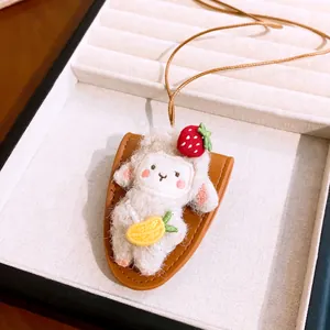 Detail view of a cute plush sheep pendant necklace with leather base and strawberry accent